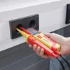 A hand is holding a voltage and continuity tester, with its probes inserted into a wall socket. Náhľad obrázku produktu