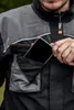 A person is putting a smartphone into the chest pocket of a work jacket. Produktbild-Vorschau