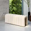 A modern living room with a beige upholstered bench in front of a large window with bamboo plants outside. Produktbild-Vorschau