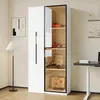 A white cabinet with glass doors displaying various items, next to a floor lamp and a desk. Náhled obrázku produktu