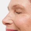 Close-up of a person's eye and nose area, showing skin texture and wrinkles. Produktbild-Vorschau