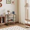 A shoe rack with shoes, a vase of flowers, and decorative items on it, placed in a room with a floor lamp and curtains. Produktbild-Vorschau