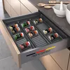 A kitchen drawer organizer filled with spice jars, with kitchen utensils and bowls on the counter. Náhled obrázku produktu