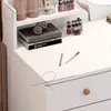 A close-up view of a white vanity table with makeup and books. Podgląd zdjęcia produktu