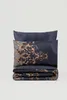 A folded duvet cover and pillowcase set with a dark blue background and ornate gold pattern. Podgląd zdjęcia produktu