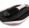 A pink and gold hair dryer brush is placed inside a black fabric pouch with a pink trim. Produktbild-Vorschau