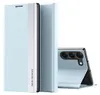 A light blue smartphone case is shown standing upright, with a second phone case partially visible behind it. A smartphone with a triple camera setup is shown leaning against the second case. Anteprima dell’immagine prodotto
