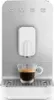 A front-facing shot of a SMEG coffee machine with a cup of espresso. Voir les images du produit