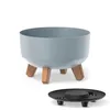 A light gray planter with wooden legs and a black drainage tray are shown against a white background. Náhľad obrázku produktu
