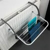 A white metal drying rack with three towels hanging on it, attached to a white radiator. Produktbild-Vorschau