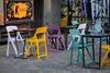 An outdoor seating area with colorful plastic chairs and tables. Produktbild-Vorschau