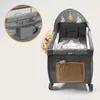 A baby in a playpen with a mobile and a changing station attachment. Produktbild-Vorschau