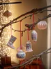 Christmas ornaments hanging from a tree branch with bokeh lights in the background. Produktbild-Vorschau