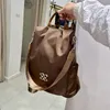 Brauner Nylonrucksack mit hellbraunen Trägern und silberner Hardware, gehalten von einer Hand Anteprima dell’immagine prodotto