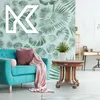 A living room scene with a teal sofa, a wooden table with a plant, and a desk in the background. Produktbild-Vorschau