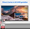 A television screen displaying a mountain landscape, with smaller inset images showing different resolutions (UHD, FHD, HD). A "TEST Bild TOP MARKE HAUS & WOHNEN" award badge is visible on the lower left. Produktbild-Vorschau