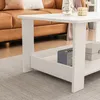 A white coffee table with a shelf is shown in a living room setting, with a brown leather sofa in the background. Produktbild-Vorschau