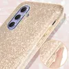 Close-up of a gold glitter phone case with a hand holding it. Produktbild-Vorschau