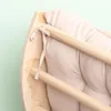 A close-up view of a wooden climbing arch with a beige cushion, showing the tie detail. Podgląd zdjęcia produktu