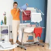 A woman is hanging clothes on a drying rack in a room. Náhled obrázku produktu