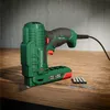 A green and black electric tacker with some staples on a wooden surface. Produktbild-Vorschau