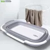 A collapsible basin is shown in a bathroom setting with a laundry basket and towels in the background. Voir les images du produit