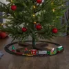 A Christmas tree with ornaments and lights, and a toy train set running around its base. Podgląd zdjęcia produktu