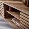 A close-up view of a wooden TV cabinet with slatted doors, showing shelves with books and a decorative vase. Anteprima dell’immagine prodotto
