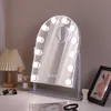 A vanity mirror with lights on a desk, with some makeup and a lamp. Produktbild-Vorschau