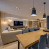 A modern living and dining room with a large sofa, dining table, and television. Anteprima dell’immagine prodotto
