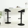 Two black bar stools are shown in a modern setting with a white counter and a plant. Voir les images du produit