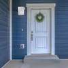 A white outdoor wall light is mounted on a blue-sided house next to a white front door decorated with a green wreath. Náhľad obrázku produktu