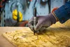 A gloved hand is using a black Sharpie marker to draw a circle on a piece of wood. The circle has a diameter of 125 marked inside it. Anteprima dell’immagine prodotto