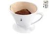 A white ceramic pour-over coffee maker with a paper filter and ground coffee inside. The coffee maker has a saucer attached. Produktbild-Vorschau
