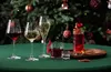 A festive table setting with various drinks in glasses and a decorated Christmas tree in the background. Produktbild-Vorschau