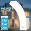 A white LED outdoor wall light with a curved design is shown against a blurred background of a house at dusk. Text overlays highlight product features. Produktbild-Vorschau