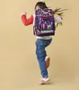 A young girl is jumping with a backpack on her back. Produktbild-Vorschau