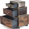 A chest of drawers designed to look like vintage suitcases, stacked on top of each other. The drawers are open, revealing black interiors. The piece has a distressed brown and metallic finish with brass-colored studs and handles. Produktbild-Vorschau