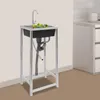 A stainless steel sink with a faucet and vegetables inside, standing on a metal frame in a room with a tiled wall and cabinets in the background. Podgląd zdjęcia produktu