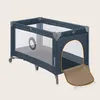 A dark blue baby travel cot with a mesh body and a tan mat extending from an opening. Anteprima dell’immagine prodotto