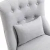 A close-up view of a tufted armchair with a small lumbar pillow. Voir les images du produit