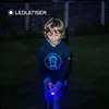 A young boy is holding a blue flashlight in the dark. Produktbild-Vorschau