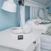 A bedside table with headphones and a digital clock next to a bed. Anteprima dell’immagine prodotto