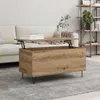 A coffee table with a lift-top mechanism is shown in a living room setting, placed on a rug in front of a sofa. A bookshelf is visible in the background. Voir les images du produit