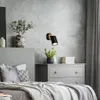 A bedroom scene with a bed, dresser, and wall lamp. Produktbild-Vorschau