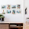 A wall decorated with a collage of framed family photos, set against a white wall above a wooden cabinet. Náhľad obrázku produktu
