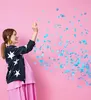 A pregnant woman is throwing blue confetti in the air. Produktbild-Vorschau