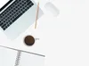 A flat lay of a laptop, coffee cup, pencil, and notebook on a white background. Produktbild-Vorschau