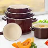 A set of brown enamel pots and pans are displayed on a white surface with some vegetables in the foreground. Náhled obrázku produktu