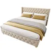A tufted beige upholstered bed with yellow and patterned throws. Voir les images du produit
